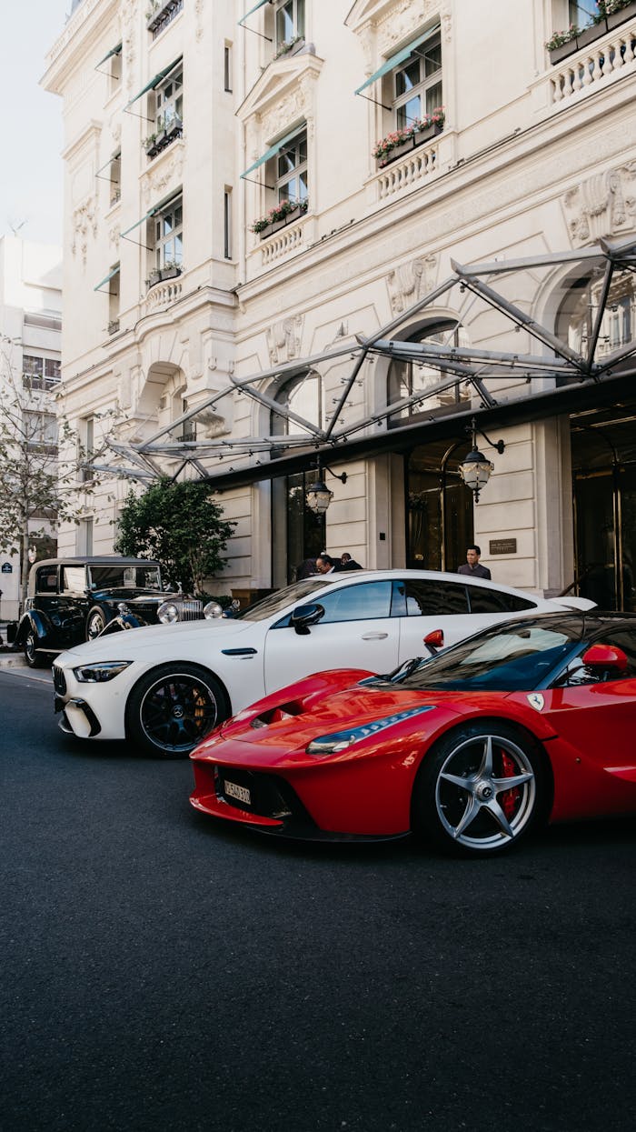 A lineup of luxury sportscars parked in front of a classic Parisian building.